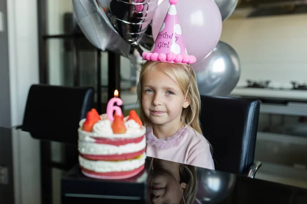 Beltéri felvétel elég vidám kislány szőke haj elfújja a gyertyát, ünnepli 6 éves születésnapját, viselni divatos ruhát, van izgatott kifejezések. Boldog gyermekkori koncepció — Stock Fotó
