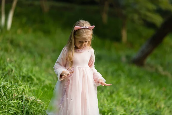 Stylowa mała dziewczynka z blond włosami rzucająca konfetti w parku. Urodziny na świeżym powietrzu, zabawy dla dzieci — Zdjęcie stockowe