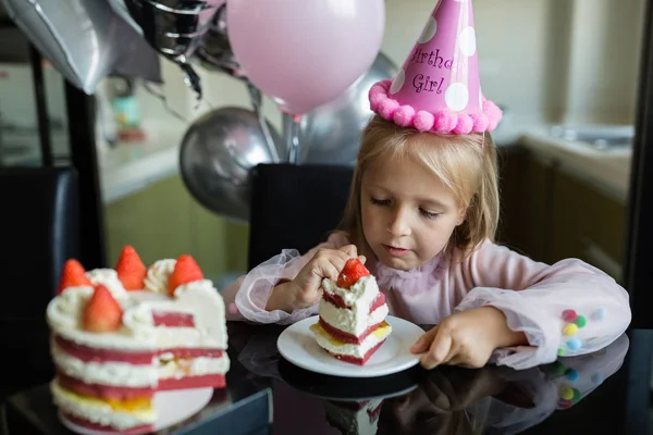 Beltéri felvétel elég vidám kislány szőke haj elfújja a gyertyát, ünnepli 6 éves születésnapját, viselni divatos ruhát, van izgatott kifejezések. Boldog gyermekkori koncepció — Stock Fotó