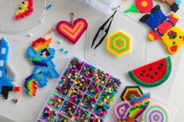 Şirin küçük kız termo mozaikle oyuncak yapıyor. Geliştirme, modellik, eğitim, sıcak plastikle tasarım. Modern teknolojiler. Diy..