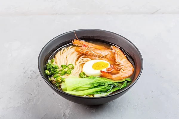 Aziatische noedelsoep, ramen met garnalen, groenten en ei in zwarte kom op grijze betonnen ondergrond. Flat lay, Bovenaanzicht, maquette, overhead. Gezond voedselconcept — Stockfoto