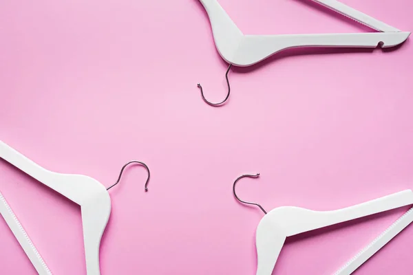 Perchas de madera blancas sobre fondo rosa pastel. Moda femenina blog venta tienda promo diseño concepto de compras. plancha, vista superior, maqueta, techo — Foto de Stock