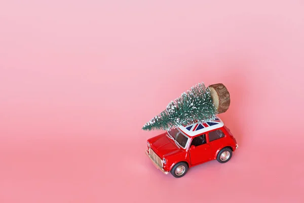 중국 - 2019 년 10 월 15 일: 분홍색 종이 배경에 크리스마스 트리가 있는 빨간 장난감 자동차. 겨울 배달 , Xmas, Happy New Year 2020 celebration 컨셉트. 인사 카드, 흉내 — 스톡 사진