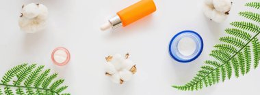 Doğal organik kozmetiklerle yatıyordu: serum, beyaz arka planda yeşil yapraklı krem. Cilt bakımı, kozmetoloji, cilt bakımı. Güzellik sertifikası, blog tarzı. Üst görünüm, üst görünüm, genel görünüm