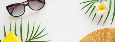 Güneş kremi, hasır şapka, palmiye yaprağı, güneş gözlüğü. Beyaz arka planda spf kremi ve fotokopi alanı. Tam üstte. Parlak yaz, tatiller, cilt bakımı. Düz yatış, şablon, model