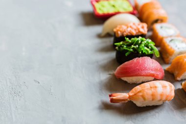 Geleneksel Japon restoranının suşi, zencefil, soya sosu, çimento grisi arka planda wasabi ile en üst görüntüsü. Çevrimiçi gıda teslimatı kavramı