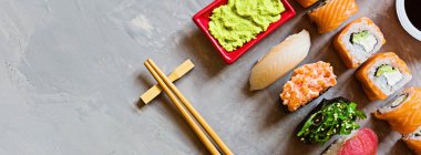 Geleneksel Japon restoranının suşi, zencefil, soya sosu, çimento grisi arka planda wasabi ile en üst görüntüsü. Çevrimiçi gıda teslimatı kavramı