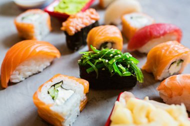 Geleneksel Japon mutfağında suşi, zencefil, soya sosu, çimento gri arka planda wasabi, dalga geç, düz yat. Çevrimiçi gıda teslimatı kavramı
