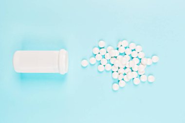 Pastel mavi arka planda beyaz haplar. Düz konum, üst görünüm, genel görünüm, model, şablon, kopyalama alanı. Eczane ve tıbbi konsept