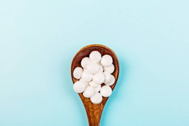 Pastel mavi arka planda beyaz haplar. Düz konum, üst görünüm, genel görünüm, model, şablon, kopyalama alanı. Eczane ve tıbbi konsept