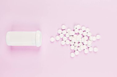 Pastel pembe arka planda beyaz haplar. Düz konum, üst görünüm, genel görünüm, model, şablon, kopyalama alanı. Eczane ve tıbbi konsept