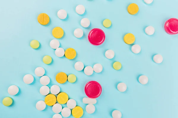 Pastillas de colores sobre un fondo azul pastel. Colocación plana, vista superior, techo, maqueta, plantilla. Farmacia y concepto médico — Foto de Stock