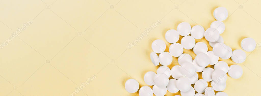 White pills on a pastel yellow background. Flat lay, top view, overhead, mockup, template, copy space. Pharmacy and medical concept