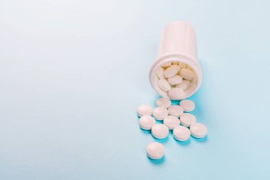 Pastel mavi arka planda beyaz haplar. Düz konum, üst görünüm, genel görünüm, model, şablon, kopyalama alanı. Eczane ve tıbbi konsept