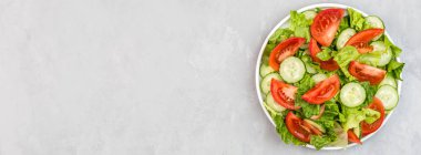 Masada sağlıklı vejetaryen yemeği, taze domatesli sebze salatası, salatalık, marul, gri beton arka planda kırmızı soğan. Diyet menüsü. Üst Manzara. Düz konum, model, kopyalama alanı olan şablon