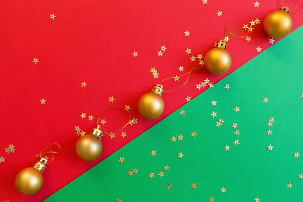 Composición navideña. Juguete dorado sobre fondo rojo y verde con confeti dorado. concepto de año nuevo. Tarjeta de felicitación, celebración de Navidad 2020. plano, vista superior, espacio para copiar, maqueta — Foto de Stock
