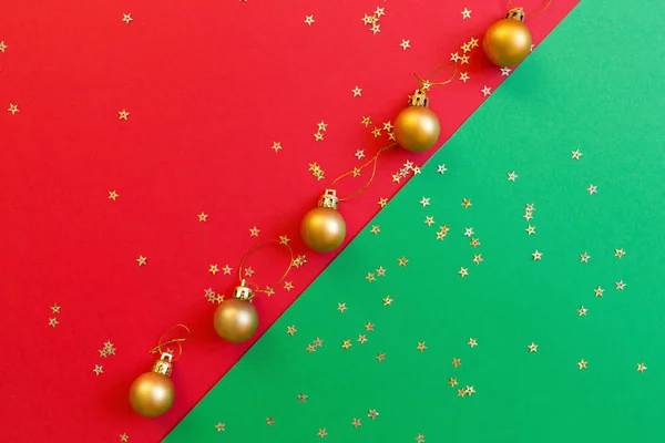 Composition de Noël. Jouet doré sur fond rouge et vert avec confettis dorés. nouvelle année concept. Carte de voeux, célébration de Noël 2020. Plat, vue du dessus, espace de copie, maquette — Photo