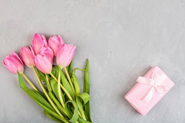 Yukarıdan laleler ve gri beton arka planda fotokopi alanı olan hediye kutusuna bak. Kadınlar Günü, 8 Mart Sevgililer Günü, 14 Şubat. Düz yatış stili, üst görünüm, model, şablon, genel giderler. Tebrik kartı