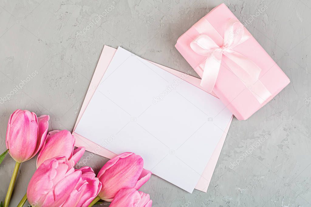 View from above tulips and gift box with copy space on gray concrete background. Womens day, 8 March Valentines day, 14 february. Flat lay style, top view, mockup, template, overhead. Greeting card