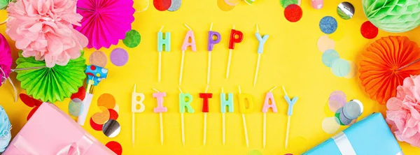 Happy birthday greeting text maked with candles and decorated with confetti on yellow background, top view. Flat lay style. Mockup, template — Stock Photo, Image