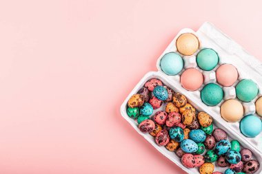 Renkli bıldırcınlı şık bir arkaplan, pembe kağıda yazılı metin için paskalya yumurtaları. Düz konum, üst görünüm, model, genel görünüm, şablon