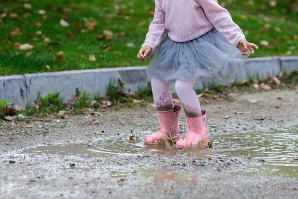 Feet of child in pink rubber boots jumping over a puddle in the rain — Stock Photo, Image