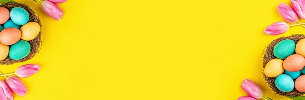 Latar belakang bergaya dengan telur Paskah berwarna-warni diisolasi dengan latar belakang kuning dengan bunga tulip merah muda. Rata lay, top view, mockup, overhead, template — Stok Foto