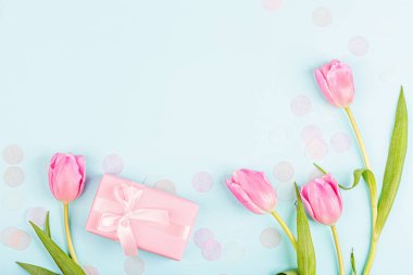 Yukarıdan laleleri ve mavi üzerinde fotokopi alanı olan hediye kutusunu izle. Kadınlar Günü için arka plan, 8 Mart Sevgililer Günü, 14 Şubat. Düz yatış stili, üst görünüm, model, şablon, genel giderler. Tebrik kartı