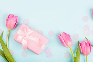 Yukarıdan laleleri ve mavi üzerinde fotokopi alanı olan hediye kutusunu izle. Kadınlar Günü için arka plan, 8 Mart Sevgililer Günü, 14 Şubat. Düz yatış stili, üst görünüm, model, şablon, genel giderler. Tebrik kartı