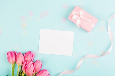 Yukarıdan laleleri ve mavi üzerinde fotokopi alanı olan hediye kutusunu izle. Kadınlar Günü için arka plan, 8 Mart Sevgililer Günü, 14 Şubat. Düz yatış stili, üst görünüm, model, şablon, genel giderler. Tebrik kartı