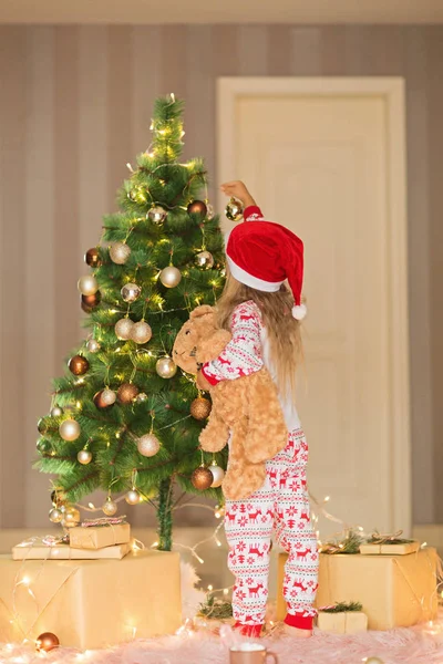 Jolie fille blonde de 5 ans décorant arbre de Noël. Chambre décorée avec des guirlandes de Noël. intérieur de la maison, Noël fête, heureux nouveau concept année 2020 — Photo