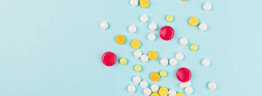 Pastel mavi arka planda renkli haplar. Düz yatış, üst görünüm, genel görünüş, model, şablon. Eczane ve tıbbi konsept