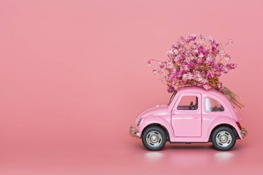 Changxing, Çin - 15 Ekim 2019: pembe arka planda çiçek buketi teslim eden pembe retro oyuncak araba. Sevgililer Günü, 14 Şubat kartı. Uluslararası Kadınlar Günü 8 Mart, Anneler Günü, Doğum günü hediyesi. Boşluğu kopyala, modelle, şablonu en aza indir
