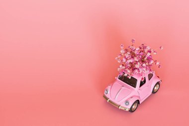 Changxing, Çin - 15 Ekim 2019: pembe arka planda çiçek buketi teslim eden pembe retro oyuncak araba. Sevgililer Günü, 14 Şubat kartı. Uluslararası Kadınlar Günü 8 Mart, Anneler Günü, Doğum günü hediyesi. Boşluğu kopyala, modelle, şablonu en aza indir