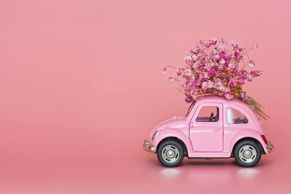 stock image Changxing, China - October 15, 2019: Pink retro toy car delivering bouquet of flowers on pink background. Valentine day, February 14 card. International women day 8 March, mother day, birthday gift. Copy space, mock up, template, minimal