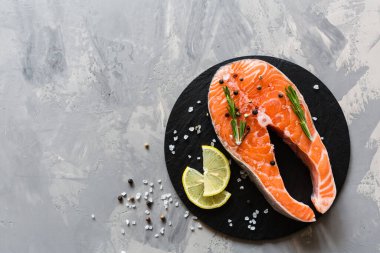 Koyu taş arka plan üzerinde baharat ile taze çiğ somon balık biftek. Balık, üst görünüm, düz yatıyordu, mockup, havai yapılmış Yaratıcı düzeni. Sağlıklı gıda kavramı