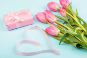 tulipány a dárková krabice na modré. Pozadí pro den žen, 8. března Valentýna, 14. února. Byt ležel styl, horní pohled, maketa nahoru, šablona, režie. Pozdrav