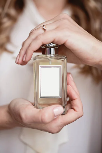 Woman hands holding bottle of perfume.