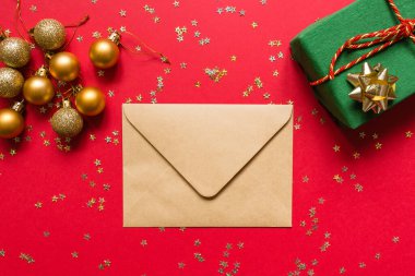 Noel kompozisyonu. Zarf, paket hediye, kırmızı arka planda altın konfetili oyuncaklar. Yeni yıl konsepti. Kutlama kartı, xmas kutlaması 2020. Düz konum, üst görünüm, kopyalama alanı, modelleme