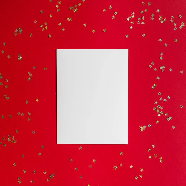 Composition de Noël. Papier blanc blanc sur fond rouge avec confettis dorés. Vacances d'hiver, concept de nouvelle année. Carte de voeux, célébration de Noël 2020. Plat, vue du dessus, espace de copie, maquette — Photo