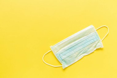 Sarı arka planda mavi tıbbi koruyucu maskeler. Üst görünüm, düz görünüm, hiç kimse, boşluğu kopyala, modelle, şablon.