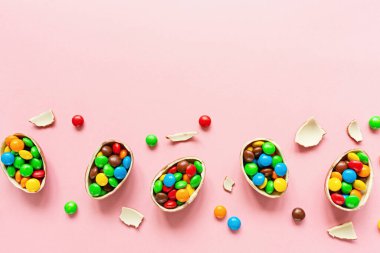 Paskalya yumurtaları ve pembe kağıtta renkli şekerler. düz konum, üst görünüm, genel görünüm, kopyalama alanı, şablon, modelleme.