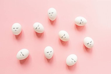 Tatlı yüzlü yaratıcı paskalya yumurtaları ve pastel pembe arka planda uykulu gözler. Mutlu Paskalyalar. Düz konum, üst görünüm, model, şablon, genel görünüm, boşluğu kopyala.