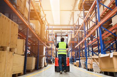 Depo çalışanı üniformalı bir forklift kullanıyor ve modern otomatik depoda kutuları var. Kutular deponun raflarında. Depo, makine konsepti. Stokta lojistik.
