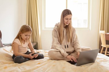 Anne, karantina ve tecrit sırasında evden çalışıyor. Kızı telefonla konuşuyor. Coronavirüs salgını, grip salgını ve Covid-19 Ncov. Serbest meslek, çevrimiçi eğitim, evde kalma kavramı.