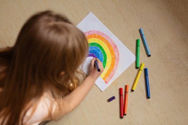 Covid-19 karantinası sırasında evde gökkuşağı boyayan bir çocuk. Coronavirus önleme için sosyal medya kampanyası için evinizde kalın, hepimiz iyi olalım, koronavirüs salgını sırasında umut.