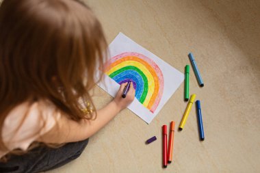 Covid-19 karantinası sırasında evde gökkuşağı boyayan bir çocuk. Coronavirus önleme için sosyal medya kampanyası için evinizde kalın, hepimiz iyi olalım, koronavirüs salgını sırasında umut.