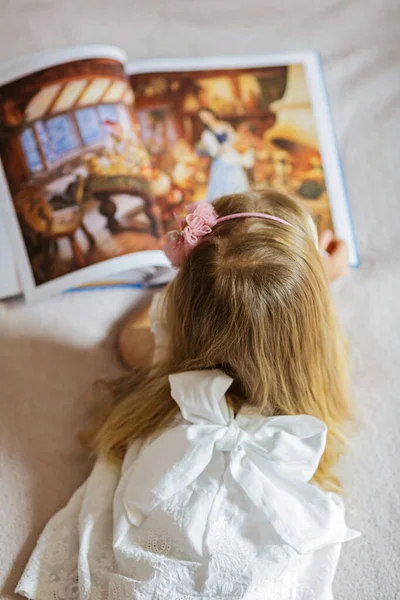 可爱的小女孩穿着时髦的白色衣服看书 小孩坐在房间的床上 在Coronavirus Covid 19封锁期间呆在家里 — 图库照片