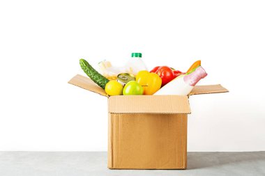 Fotokopi alanı olan beyaz arka planda çeşitli akıllı yiyeceklerin olduğu bağış kutusu. Yiyecek bağışları ya da yemek servisi konsepti. Coronavirus covid-19 kilitlenmesi sırasında online alışveriş.