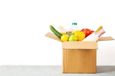 Fotokopi alanı olan beyaz arka planda çeşitli akıllı yiyeceklerin olduğu bağış kutusu. Yiyecek bağışları ya da yemek servisi konsepti. Coronavirus covid-19 kilitlenmesi sırasında online alışveriş.